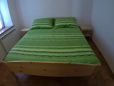 a bed in a room with green sheets and pillows at Lesjakova Domačija in Bovec