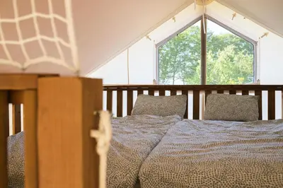 a bed in a room with a large window at Glamping Kolpa Resort in Gradac