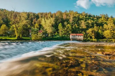 a small house on the shore of a river at Glamping Kolpa Resort in Gradac