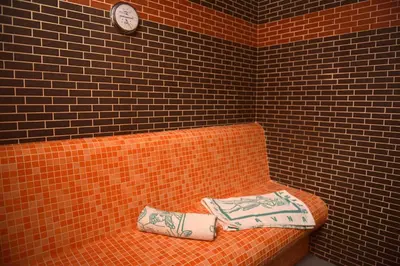 an orange couch with two pillows and a clock on a brick wall at Apartma Kamp Ajdovščina in Ajdovščina