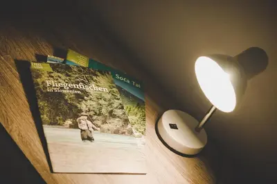 a table with a book and a lamp and a book at Apartma Trebušca in Dolenja Trebuša