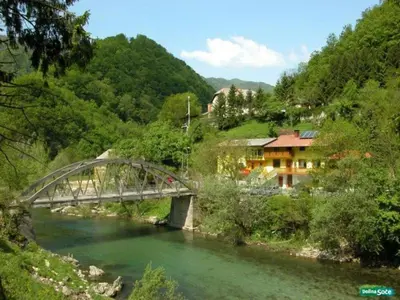 a bridge over a river next to a mountain at Apartma Trebušca in Dolenja Trebuša
