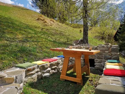 a picnic table with colorful cushions on a stone wall at Predel House in Log pod Mangartom