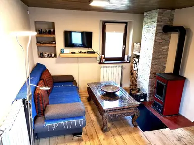 a living room with a couch and a table and a tv at Predel House in Log pod Mangartom