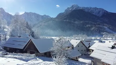 a village covered in snow with mountains in the background at Apartments Planica in Kranjska Gora