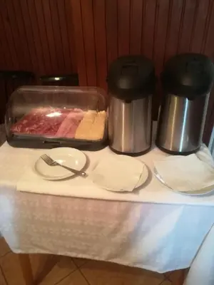 a table with two crock pots and a tray of meat at Apartments and rooms Cerkovnik in Bohinj