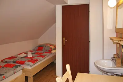 a small bedroom with a bed and a sink at Apartments and rooms Cerkovnik in Bohinj