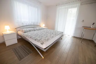 a white bedroom with a bed and two lamps at Sobe Meta in Brezje