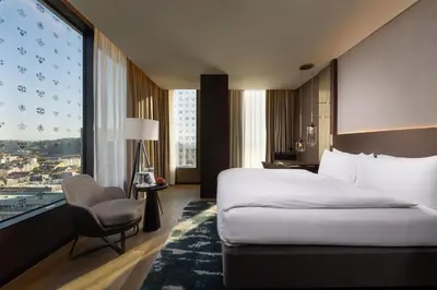 a hotel room with a bed and a chair and a window at InterContinental - Ljubljana by IHG in Ljubljana