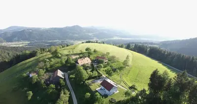 an aerial view of a house on a green hill at Razborca in Mislinja