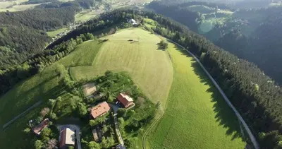 an aerial view of a large green field with a house at Razborca in Mislinja