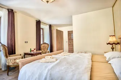 a hotel room with a bed and a chair at Hiša Linhart, Hotel & Restaurant in Radovljica