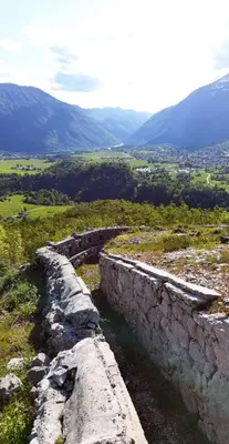 a stone wall on top of a field with mountains at Gostišče Hedvika in Kal-Koritnica