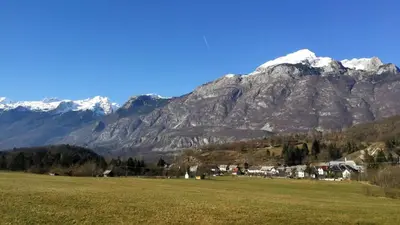 a mountain with snow capped mountains in a field at Gostišče Hedvika in Kal-Koritnica