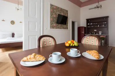 a table with croissants and cups and a bowl of fruit at Barbo Palace Apartments and Rooms in Ljubljana