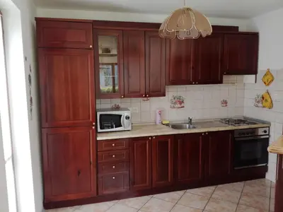 a kitchen with wooden cabinets and a microwave at Pri Mlinarju in Tolmin