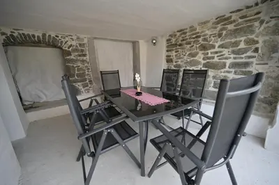a table and chairs in a room with a stone wall at Apartments Ten Sen in Kobarid