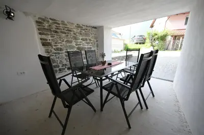 a dining room table with black chairs and a stone wall at Apartments Ten Sen in Kobarid