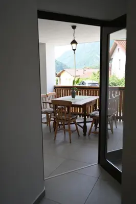 a room with a table and chairs on a balcony at Apartments Ten Sen in Kobarid