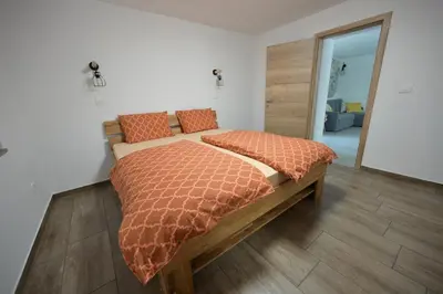 a bedroom with a large bed with orange comforter at Apartments Ten Sen in Kobarid