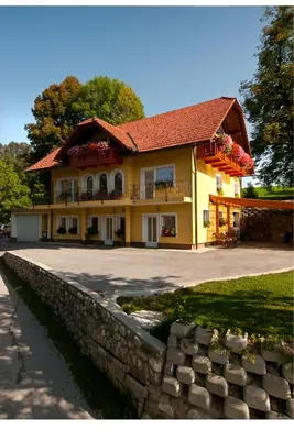 a large yellow house with a stone wall at Apartments Bernarda in Bled