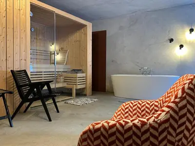 a bathroom with a tub and a table and a chair at Cosy Lodge Pokljuka in Goreljek