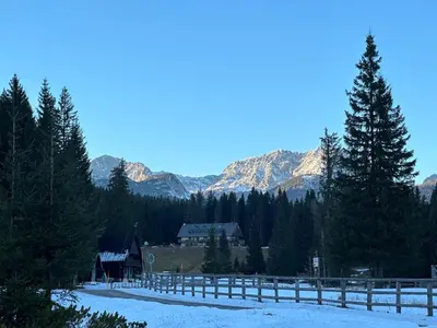 a house in the snow with mountains in the background at Cosy Lodge Pokljuka in Goreljek