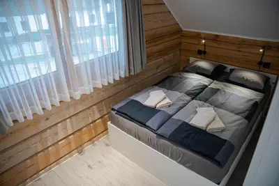a bedroom with a large bed with wooden walls at ALPEART BOHINJ HOLIDAY units in Bohinj