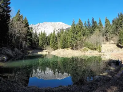 a river with a reflection of a mountain in the water at Karami Mountainhouse in Tržič