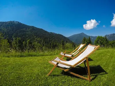 two chairs sitting in a field with mountains in the background at Karami Mountainhouse in Tržič