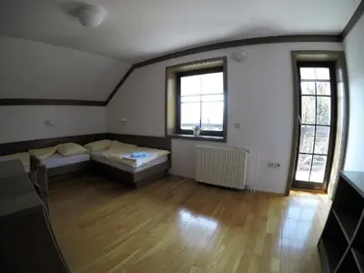 a large room with two beds and two windows at Karami Mountainhouse in Tržič
