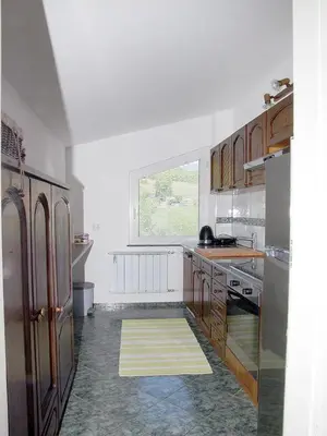 a kitchen with white walls and wooden cabinets and a window at Apartment Zupan in Maribor