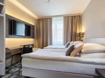 a hotel room with two beds and a desk at Hotel Center Novo Mesto in Novo Mesto