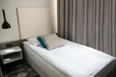 a bedroom with a white bed with a blue pillow at Hotel Center Novo Mesto in Novo Mesto
