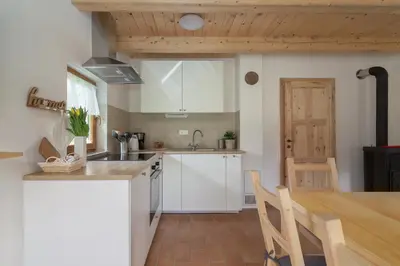 a kitchen with white cabinets and a wooden table at Holiday Homes Sara in Bled