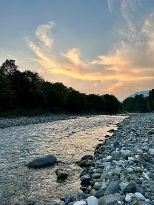 a river with rocks in the water and trees at Glamping Savinja in Ljubno