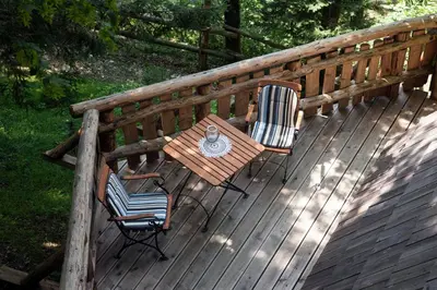 a wooden deck with a table and chairs on it at Glamping Savinja in Ljubno