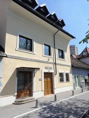 a white building with brown doors on a street at Apartments Maria in Ljubljana