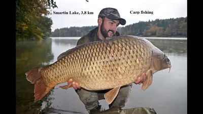a man holding a large fish in front of a lake at Apartment Janja in Vojnik