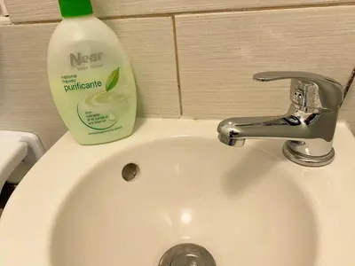 a white sink with a bottle of moisturizing detergent on it at Family Guesthouse GreenSLO in Ljubljana