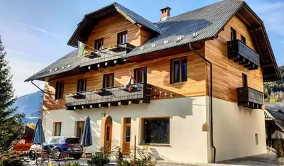 a large wooden house with a car parked in front of it at Vila Koman Jezersko in Zgornje Jezersko