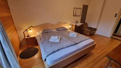 a bedroom with a large bed and a chair at Vila Koman Jezersko in Zgornje Jezersko