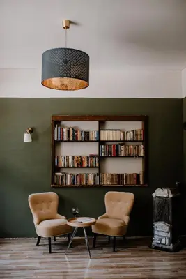 a room with two chairs and a book shelf with books at Vila Koman Jezersko in Zgornje Jezersko