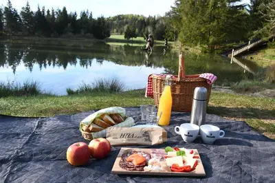 a picnic table with food and a basket of bread and drinks at Glamping Lake Bloke in Nova Vas