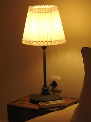 a lamp sitting on a table next to a bed at Karst Stone Cottage in Štanjel