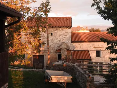 an old stone building with a grill in the yard at Karst Stone Cottage in Štanjel