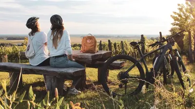 two women sitting on a bench with a bike at Hiša PRI JEZERU in Dobrovnik