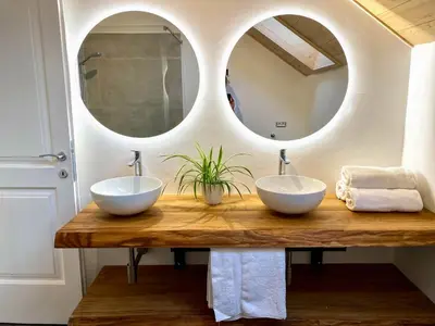 two sinks on a wooden table with two mirrors at Hiša PRI JEZERU in Dobrovnik