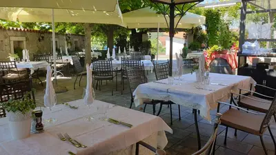 a restaurant with white tables and chairs and umbrellas at Boutique Hotel Grahor in Sežana