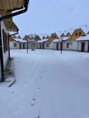a yard covered in snow with houses in the background at Apartma Jelenček in Moravske Toplice
